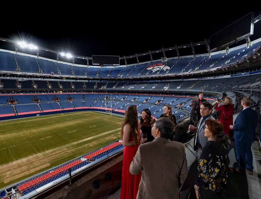 Group of ten people standing inside an empty Mile High Stadiu